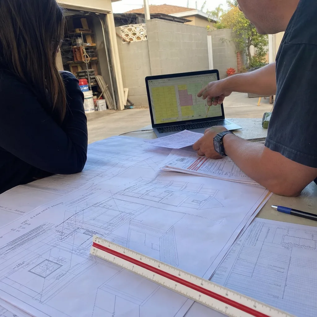 Architectural professional and client reviewing ADU design plans and permitting documents.
